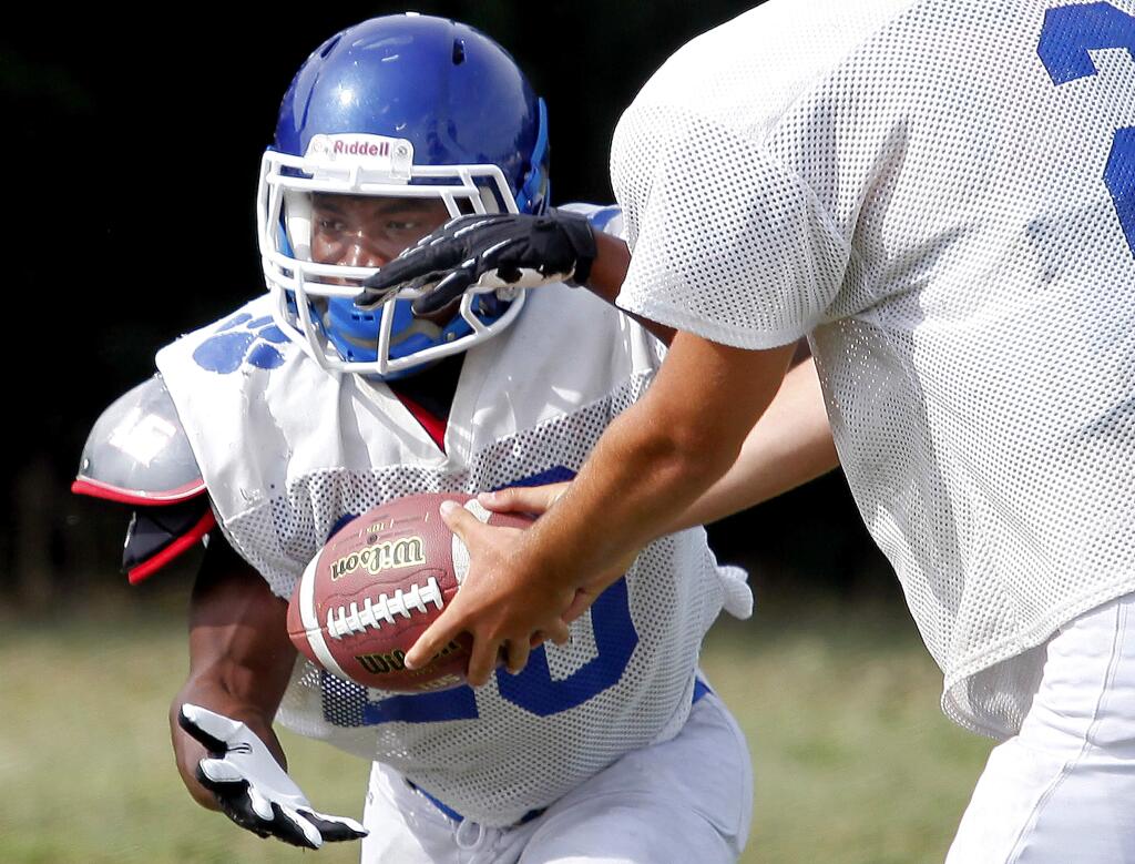 Analy High School's quarterback Will Smith, right, passes the ball off to running back Ja'Narrick James during practice in Sebastopol, Tuesday, August 12, 2014. (Crista Jeremiason / The Press Democrat)