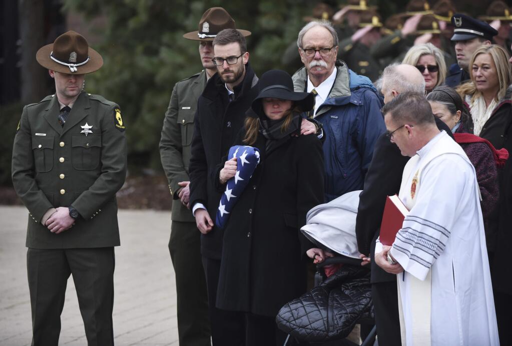 Halley Lambert holds the hand of her one-year old daughter Delaney during the funeral for her husband, Illinois State Police Trooper Christopher Lambert, at Willow Creek Community Church in South Barrington, Ill., Friday, Jan. 18, 2019. (Joe Lewnard/Daily Herald via AP)