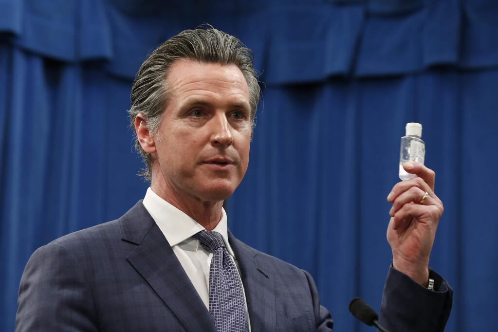 Gov. Gavin Newsom displays a bottle of hand sanitizer while saying the state would take action against price gouging because of the coronaviru. (RICH PEDRONCELLI / Associated Press)