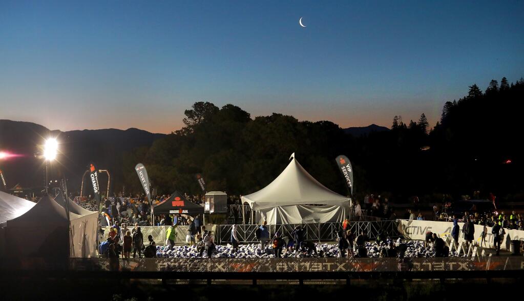 Ironman Santa Rosa volunteers arrange biking gear before dawn at the transition from swim to the ride at Lake Sonoma before dawn. (photo by John Burgess/The Press Democrat)