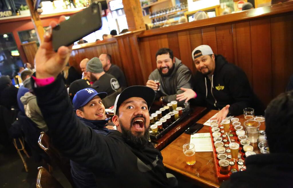Victor Arrazabal, foreground, shoots a selfie with Sergio Guadron, left, Hernan Tobar, and Victor Arana, at the Russian River Brewing Company, in Santa Rosa, on Friday, February 3, 2017. The friends travelled from Los Angeles for this year's release of Pliny the Younger.(Christopher Chung/ The Press Democrat)