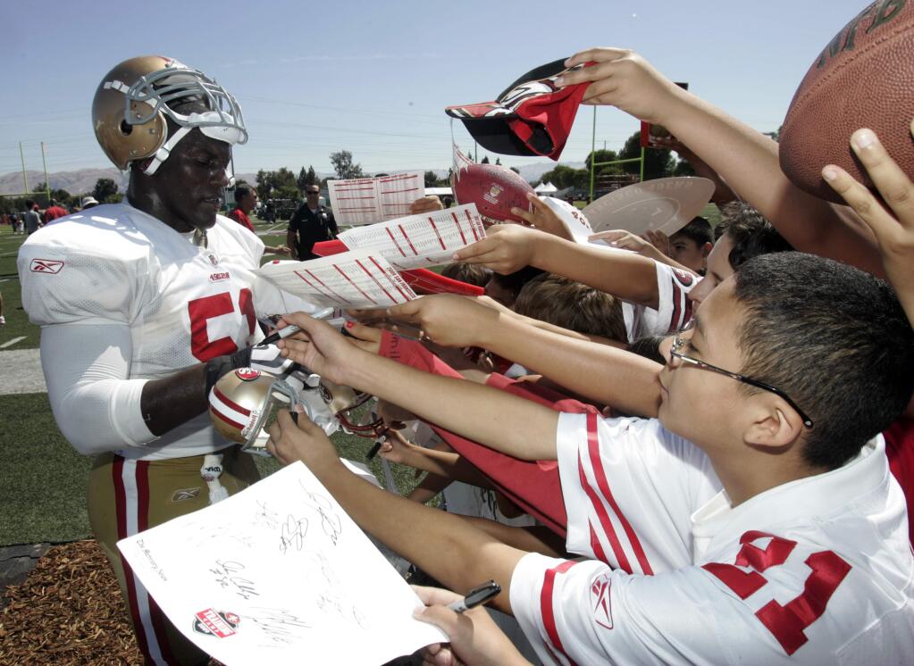 San Francisco 49ers linebacker Takeo Spikes signs autographs during NFL football training camp in Santa Clara, Calif., Saturday, Aug. 1, 2009. (AP Photo/Marcio Jose Sanchez)
