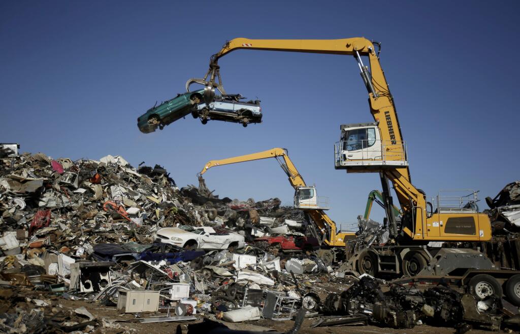 In this Friday, Dec. 1, 2017, photo, workers place old automobiles on a scrap pile to be shredded at Midwest Scrap Management in Kansas City, Mo. The company switched to a self-funded health insurance plan in March and has saved $20,000 off its projected insurance costs since. (AP Photo/Charlie Riedel)