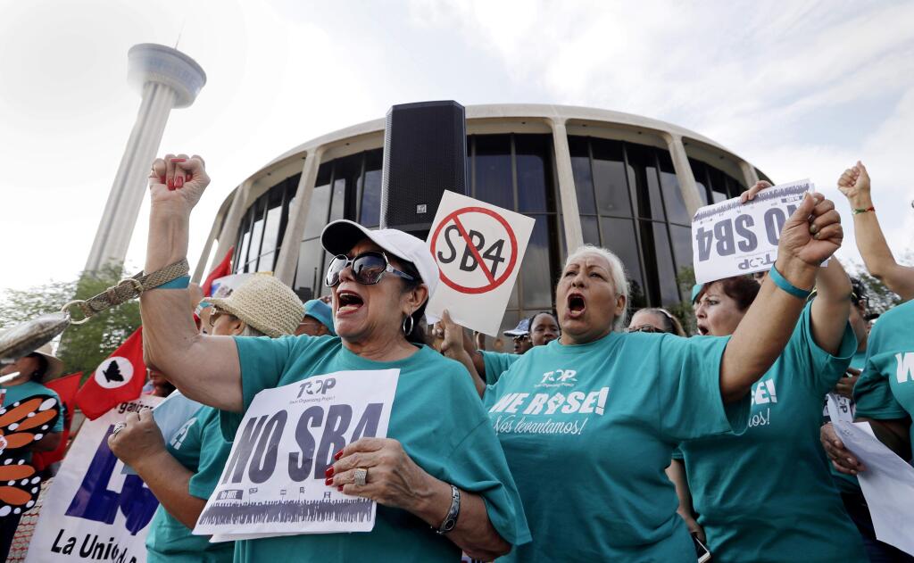 FILE - In this June 26, 2017, file photo, Lydia Balderas, left, and Merced Leyua, right, join others as they protest against a new sanctuary cities bill outside the federal courthouse in San Antonio. Even as a new Texas law targeting so-called sanctuary cities remains in legal limbo, police chiefs and sheriffs are making changes to comply, rewriting training manuals and withdrawing policies that prevented officers from asking people whether they're in the United States illegally. The law, known as Senate Bill 4, goes into effect Sept. 1 unless a federal judge in San Antonio blocks it. (AP Photo/Eric Gay, File)
