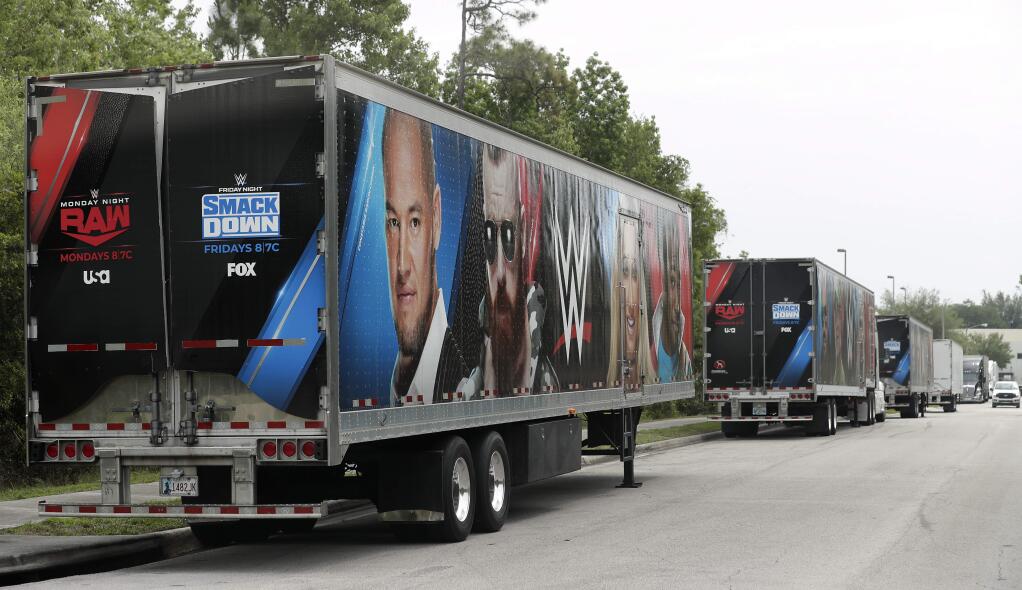 Equipment trailers are lined up at the entrance road to the WWE Performance Center Tuesday, April 14, 2020, in Orlando, Fla. Florida's top emergency official last week amended Gov. Ron DeSantis' stay-at-home order to include employees at the professional sports and media production with a national audience, if the location is closed to the public. (AP Photo/John Raoux)