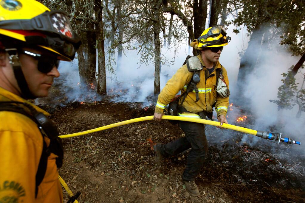 Firefighter Ryan Meier, right, of Southern Marin Fire Protection District and firefighter Jeoffrey Orman of Marin County Fire advance a hoseline during firing operations in the hills north of Highway 12 in Santa Rosa, California, on Saturday, October 14, 2017. (Alvin Jornada / The Press Democrat)