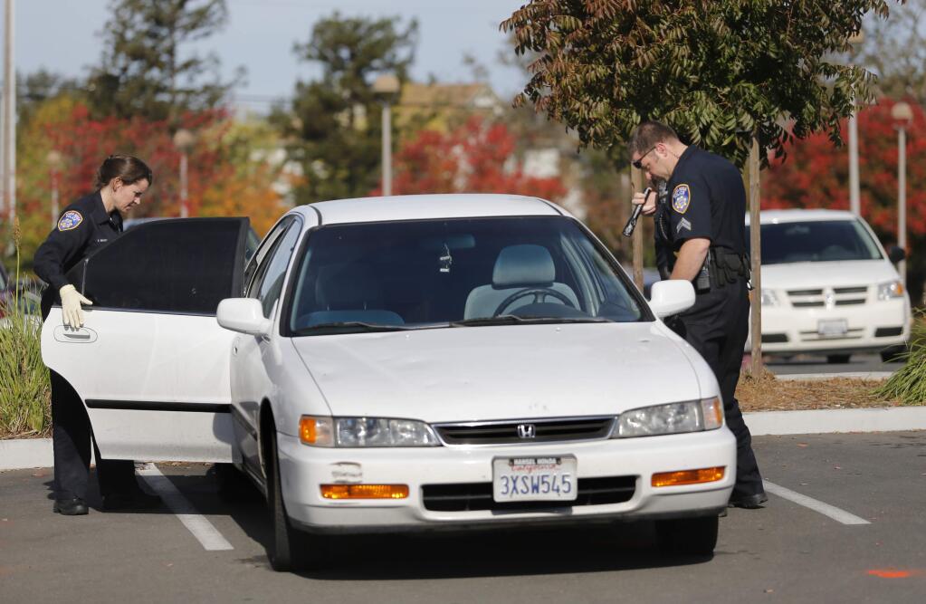 Santa Rosa police field evidence technician Shannon Brady, left, and police officer Jeff Adams check a car for evidence of a Saturday night shooting in the parking lot of the Finley Community Center on Sunday, October 23, 2016 in Santa Rosa, California . (BETH SCHLANKER/ The Press Democrat)
