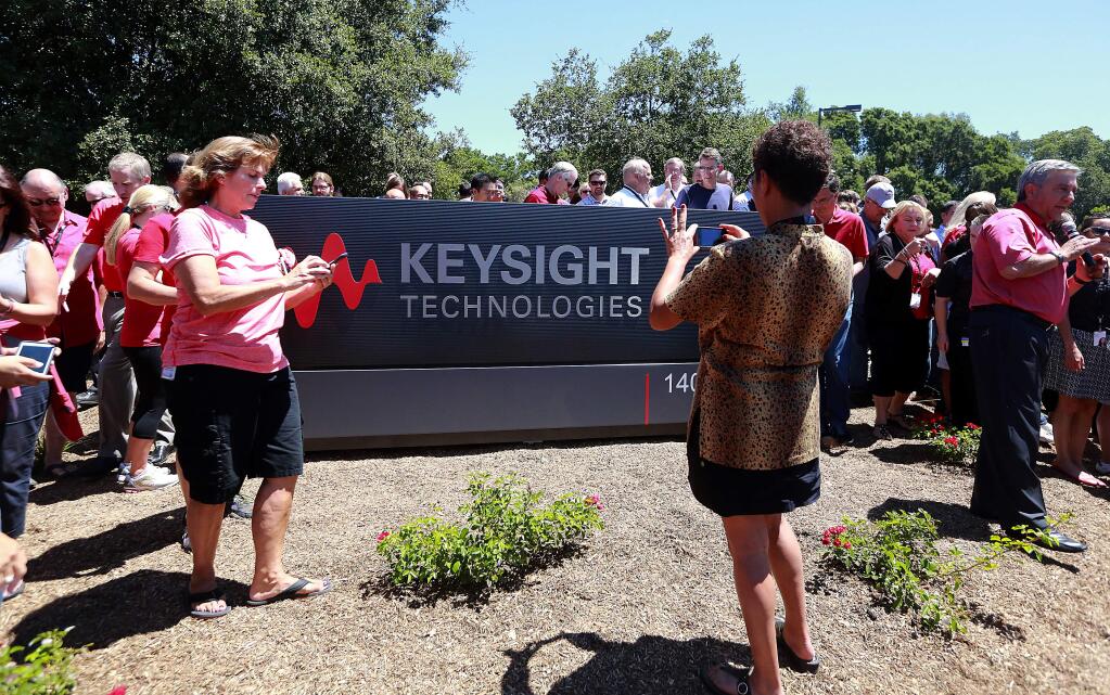 Former Agilent employees take pictures of their new Keysight Technologies sign unveiled in front of their facility on Fountaingrove Ave. on Friday afternoon.