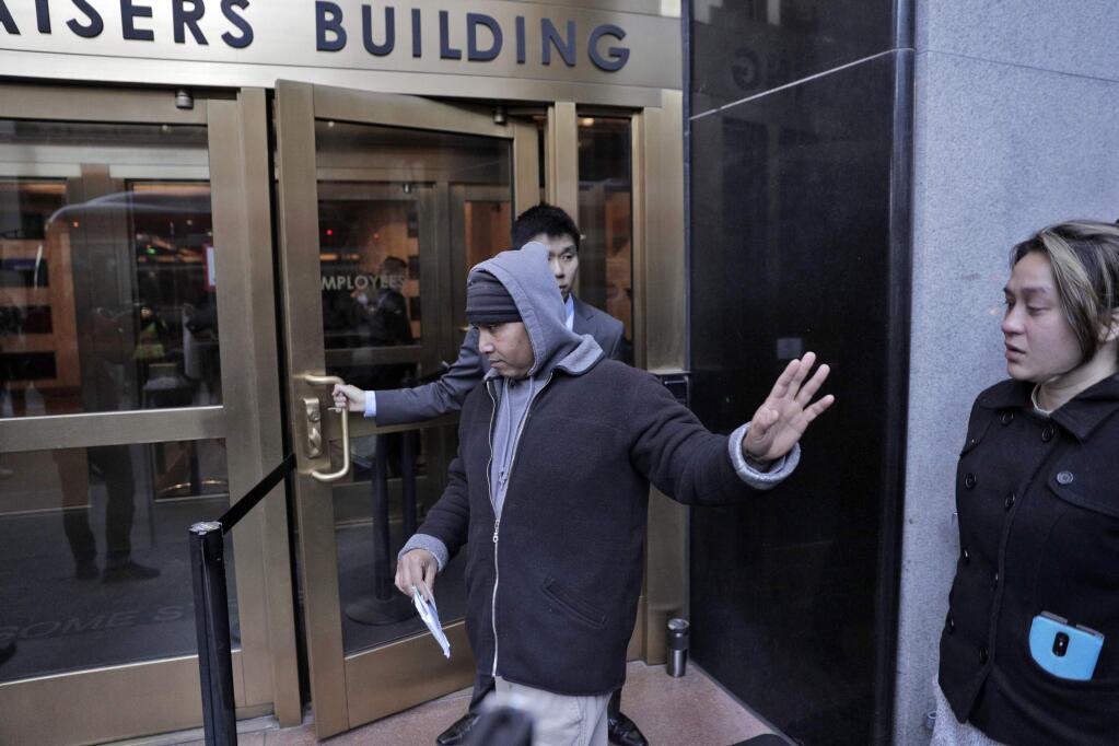 FILE - In this March 13, 2019, file photo, Hay Hov waves to supporters as he and his wife, Catherine Depooter-Hov, enter the U.S. Immigration and Customs Enforcement offices in San Francisco where he turned himself over to ICE officials. Hov and another former Cambodian refugees facing deportation for crimes committed as young adults were among seven people granted clemency Monday, May 13, by California Gov. Gavin Newsom in his first pardons since taking office in January. (Carlos Avila Gonzalez/San Francisco Chronicle via AP, File)
