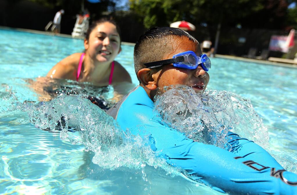 Swim instructor Isabella Lansdowne teaches Adan Velasquez, 7, how to swim during the 'Vamos a Nadar' program at the Cloverdale YMCA pool on Saturday. Regional Parks program designed to reduce drownings by teaching children how to swim while providing water-safety training to their parents. (John Burgess/The Press Democrat)