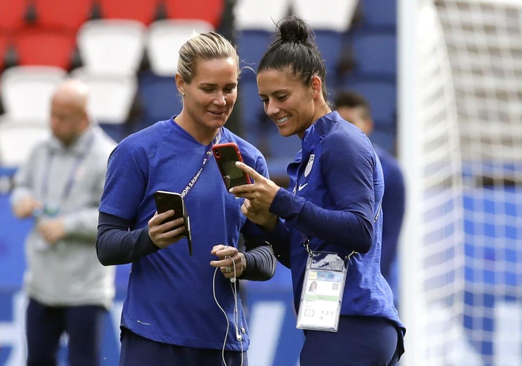 In this June 15, 2019, file photo, U.S. teammates Ashlyn Harris, left, and Ali Krieger chat during a visit to the Parc des Princes stadium a day before a game against Chile at the Women's World Cup in Paris. Many World Cup teammates have special bonds. The tie that binds U.S. defender Krieger and goalkeeperHarris is likely the strongest at the tournament. They got engaged last year and are planning a December wedding. (AP Photo/Alessandra Tarantino, File)