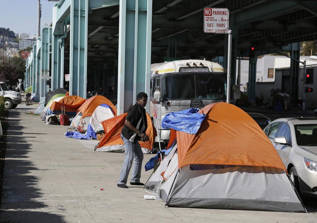 FILE - In this Feb. 23, 2016 file photo, a man stands outside his tent on Division Street in San Francisco. San Francisco voters approved a tax on the city's wealthiest companies Tuesday, Nov. 6, 2018, in an attempt to alleviate homelessness in a place where people at risk of being priced out encounter people sleeping on the streets every day. Despite opposition from the mayor and some business leaders, about 60 percent of voters supported Proposition C, but it was falling short of a two-thirds majority that would ward off litigation. (AP Photo/Eric Risberg, File)