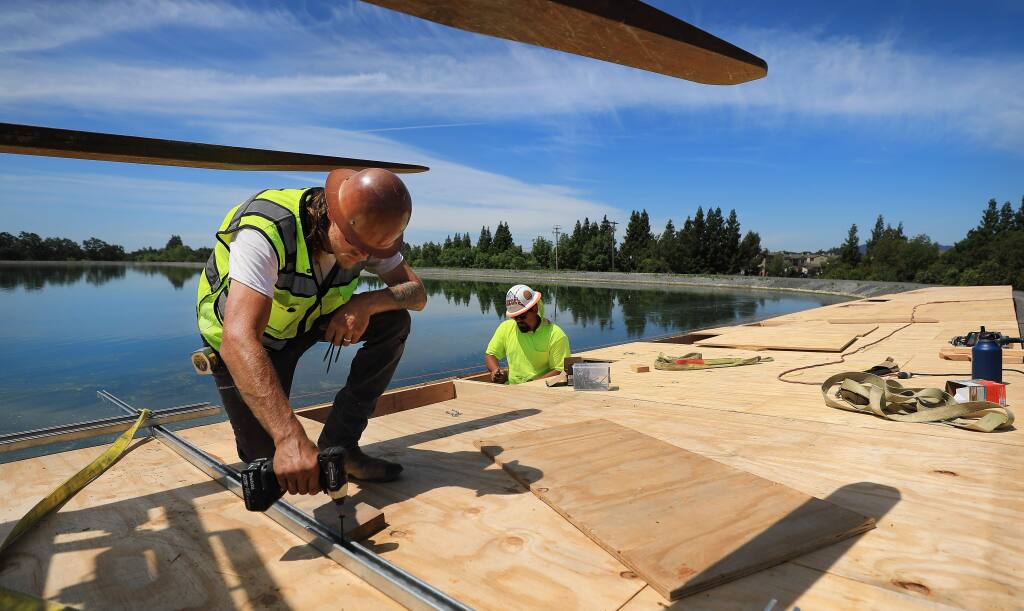 Tyger Roy, left and Shane Cook assemble platforms that will be used to to piece together solar panels on floats that will be floated in to one Windsor's effluent ponds, Wednesday, June 5, 2019. (Kent Porter / The Press Democrat) 2019