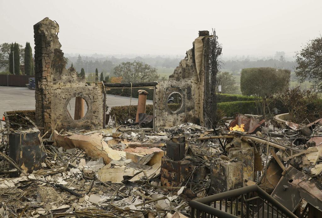 The remains of the Signorello Estate winery continue to smolder Tuesday, Oct. 10, 2017, in Napa, Calif. Worried California vintners surveyed the damage to their vineyards and wineries Tuesday after wildfires swept through several counties whose famous names have become synonymous with fine food and drink. (AP Photo/Eric Risberg)