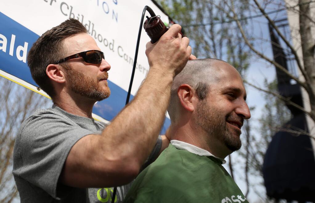 Bill Smart, right, has his head shaved by Chris Lands during the St. Baldrick's fundraiser held at KIN Restaurant in Windsor, Saturday, March 21, 2015. (Crista Jeremiason / The Press Democrat)