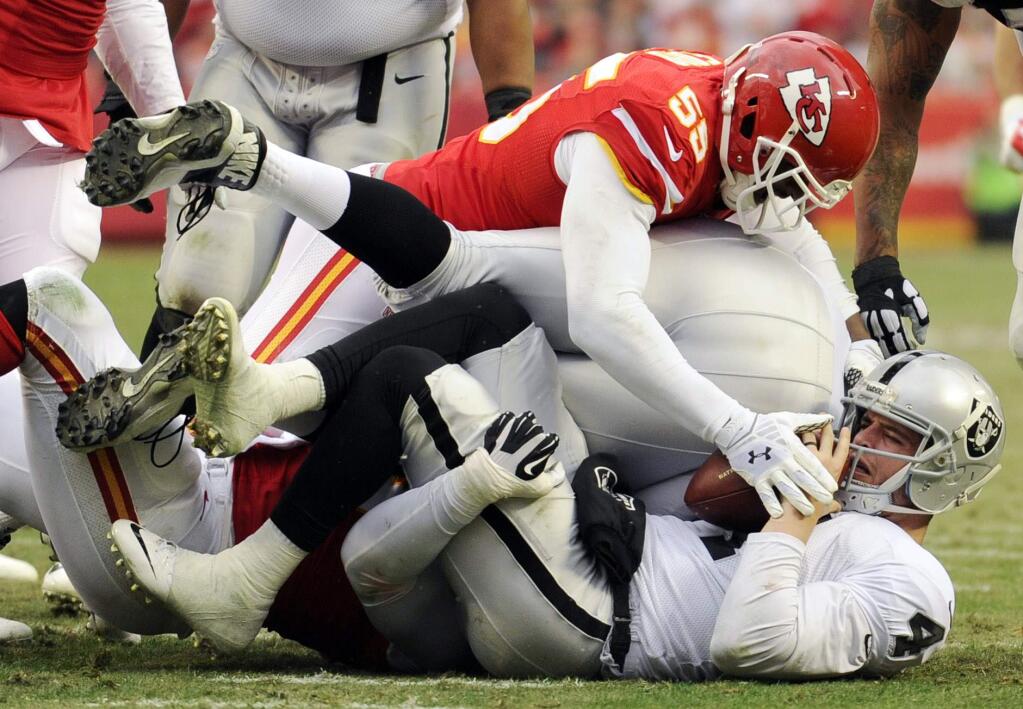 Oakland Raiders quarterback Derek Carr, bottom, is tackled by Kansas City Chiefs linebacker Dee Ford (55) during the second half of a game in Kansas City, Mo., Sunday, Dec. 14, 2014. (AP Photo/Ed Zurga)