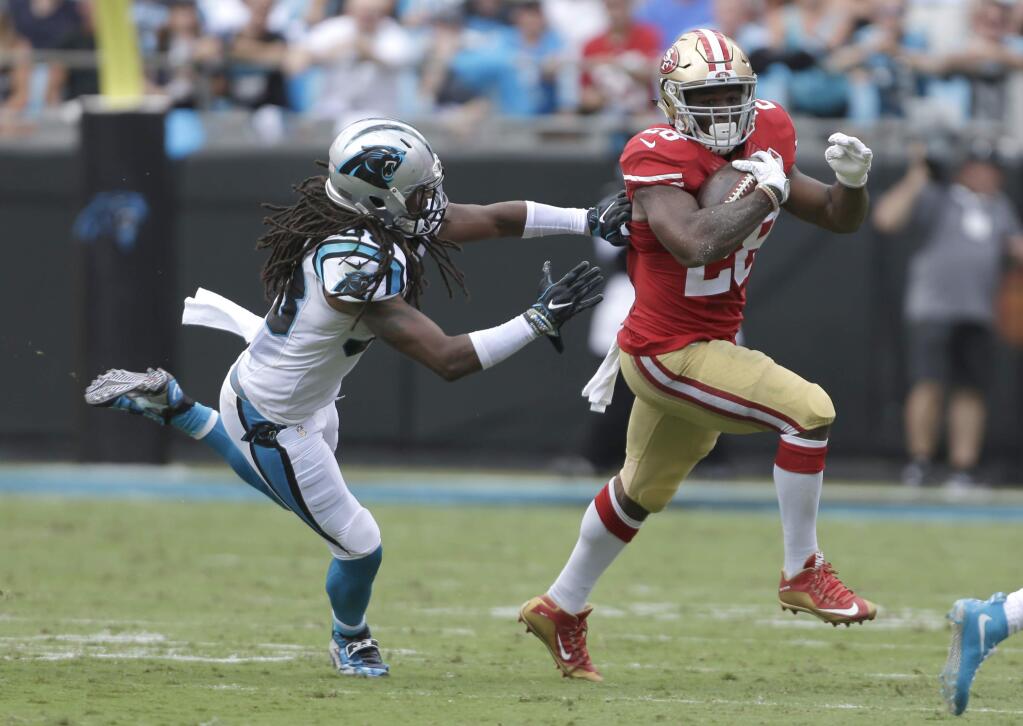 The San Francisco 49ers' Carlos Hyde runs as the Carolina Panthers' Tre Boston defends in the first quarter in Charlotte, N.C., Sunday, Sept. 18, 2016. (AP Photo/Bob Leverone)