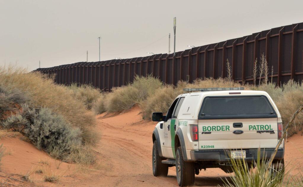 FILE - In this Jan. 4, 2016 file photo, a U.S. Border Patrol agent drives near the U.S.-Mexico border fence in Santa Teresa, N.M. A coalition of environment groups is seeking to stop work to replace existing vehicle barriers along the U.S.-Mexico border in southern New Mexico. The groups filed a lawsuit in U.S. District Court on Thursday, March 22, 2018, claiming the U.S. Department of Homeland Security does not have authority to waive environmental laws as a way to speed construction along a 20-mile stretch near the Santa Teresa port of entry.(AP Photo/Russell Contreras, File)