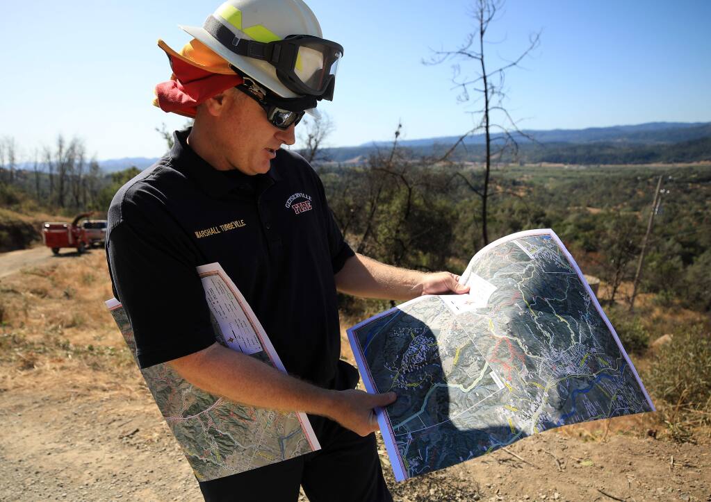 Marshall Turbeville of the Geyserville Fire Protection District looks over a map of vegetation reduction projects along private roads above Geyserville, Thursday Sept. 19, 2019. (Kent Porter / The Press Democrat