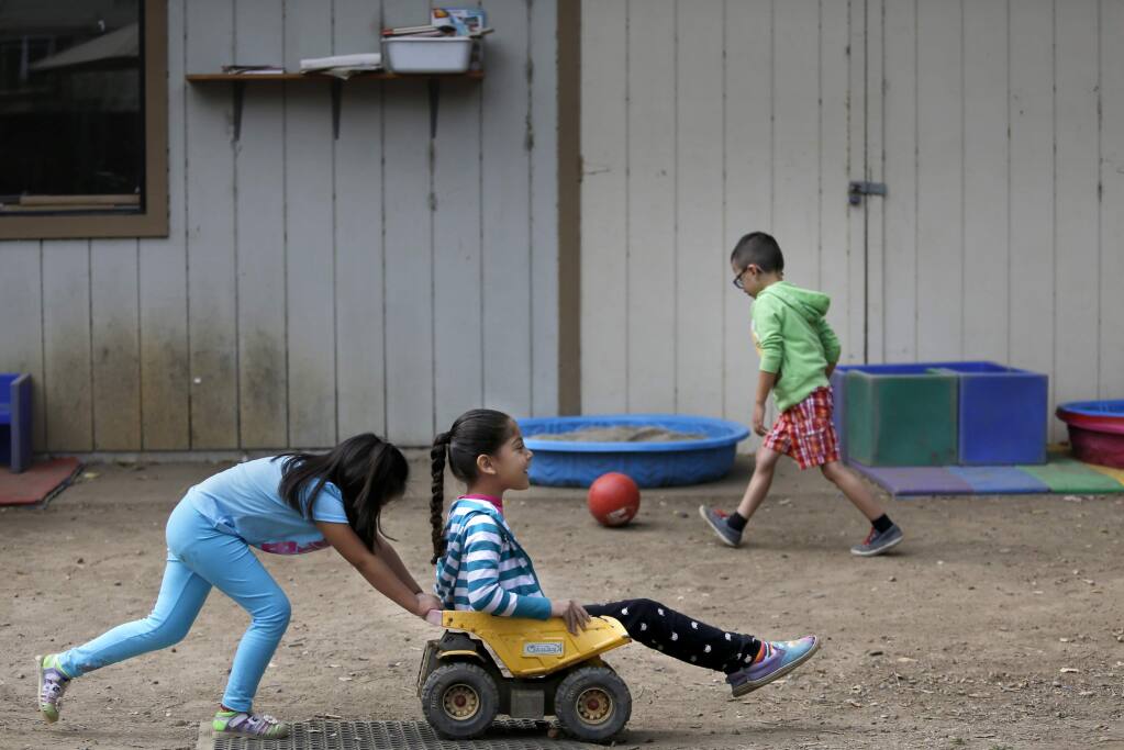 Estrella Palencia, 5, pushes Mezmerae Davenport, 5, around the schoolyard at Healdsburg Child Development Preschool in Healdsburg, on Tuesday, August 11, 2015. (BETH SCHLANKER/ The Press Democrat)