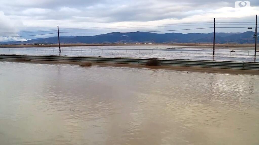 This Wednesday, Dec. 4, 2019 photo from video from KSBW-TV shows flooding on U.S.Highway 101, the area in front of the guardrail, and a large field beyond near the town of Chualar in Northern California's Monterey County. Several schools remain closed Thursday in Northern California town after heavy rain led to flooding on U.S. Highway 101 in Monterey County, officials said. (KSBW-TV via AP)