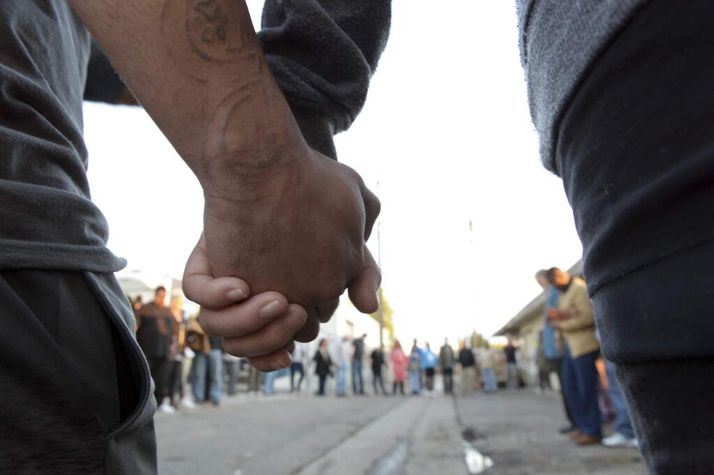 Community members and faith leaders from On Ramps Covenant Church hold hands during a prayer and vigil in the alley behind the Catholic Charities' Fresno Family Resource Center to honor the three shooting victims that were killed by a gun man on Tuesday morning, April 18, 2017, in Fresno, Calif. Two of the victims were shot near the building by suspect Kori Ali Muhammad. (Silvia Flores/The Fresno Bee via AP)