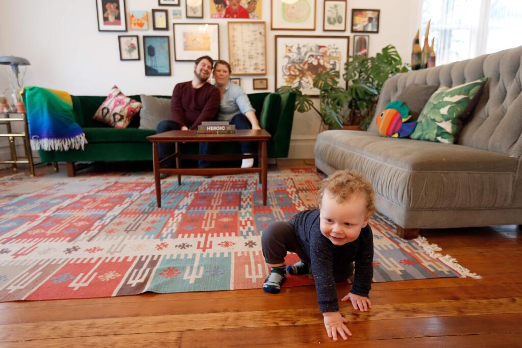 Levi Backman, 1, crawls around the living room while his parents Daniel and Madeline watch from the couch at their home in Petaluma, California on Saturday, January 16, 2016. The Backmans were given a Biennial Preservation Award by Heritage Homes of Petaluma for their restoration work on their 1890's Folk Victorian house designed by architect Brainerd Jones. (Alvin Jornada / The Press Democrat)