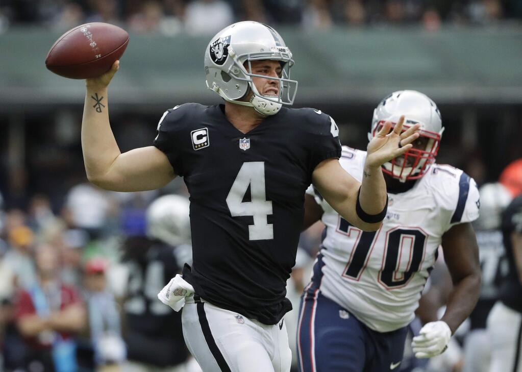 Oakland Raiders quarterback Derek Carr passes under pressure from New England Patriots defensive tackle Adam Butler during the first half Sunday, Nov. 19, 2017, in Mexico City. (AP Photo/Rebecca Blackwell)