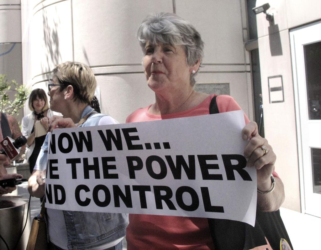 Jane Carson-Sandler, of South Carolina, who was raped by the so-called Golden State Killer in 1976, holds a sign with a message to her attacker in Sacramento, Calif.,Thursday, July 12, 2018, outside the Sacramento County jail after she and other victims and survivors attended a brief court hearing and saw the accused attacker, Joseph DeAngelo, for the first time. (AP Photo/Don Thompson)