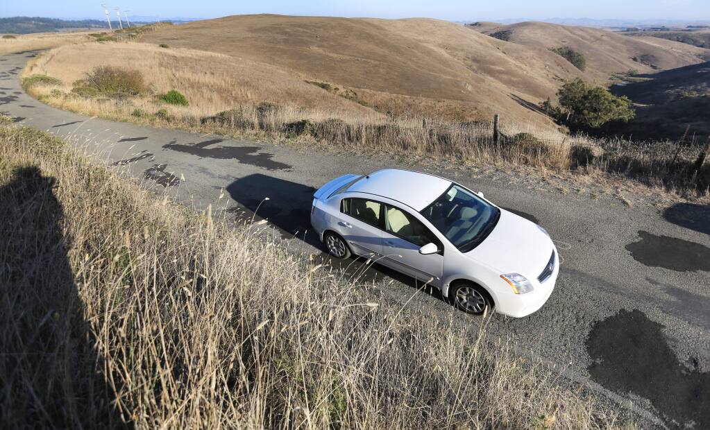 A car makes its way over filled-in potholes on Bay Hill Road east of Bodega Bay. (KENT PORTER/ PD FILE, 2013)