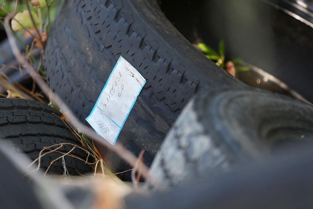 A tire with a label attached is among a large number of tires dumped along Highway 101 and the Russian River, four miles south of Hopland, on Tuesday, October 1, 2019. (Christopher Chung/ The Press Democrat)