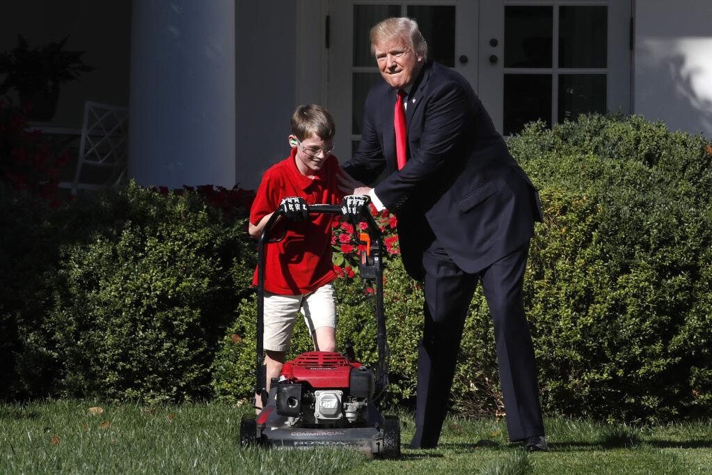 Frank Giaccio, 11, of Falls Church, Va., left, is encouraged by President Donald Trump, Friday, Sept. 15, 2017, while he mowed the lawn in the Rose Garden at the White House in Washington. The 11-year-old, who wrote the president requesting to mow the lawn at the White House, was so focused on the job at hand the he didn't notice the president until he was right next to him. (AP Photo/Jacquelyn Martin)