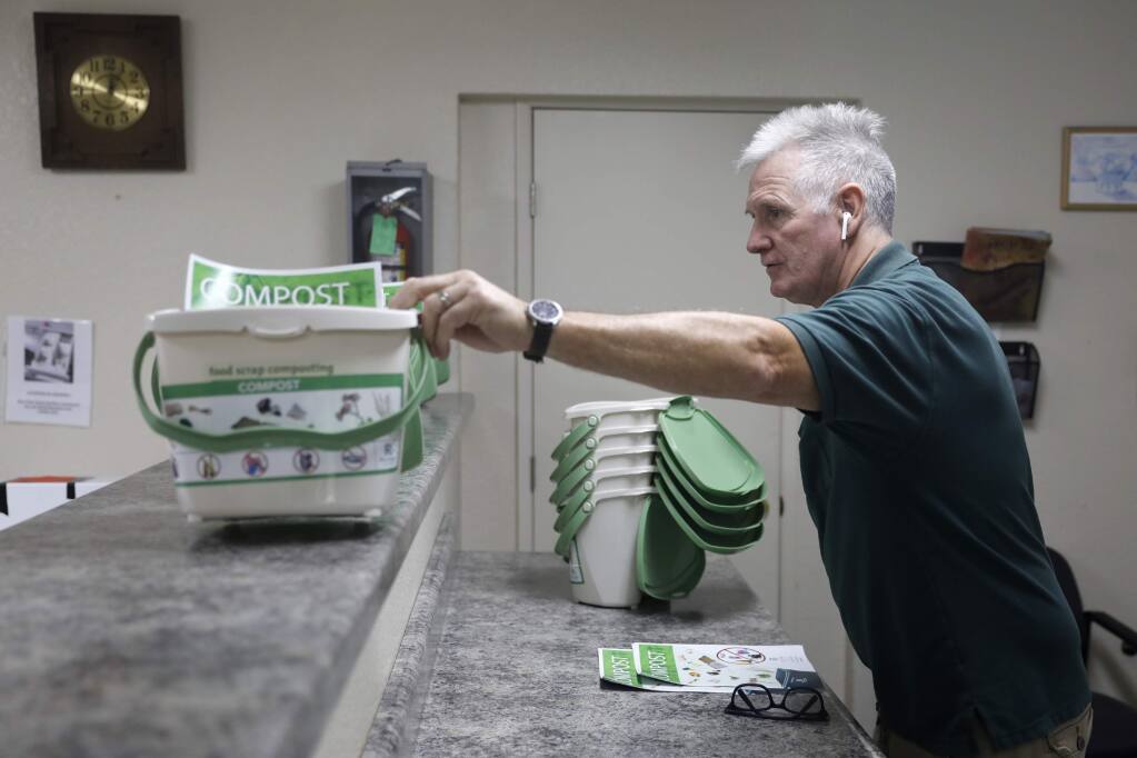Pine Creek Properties manager Harry Brown sets out free compost bins for tenants in the laundry room of the Coddington Mall Apartments on Thursday, August 30, 2018 in Santa Rosa, California . (BETH SCHLANKER/The Press Democrat)
