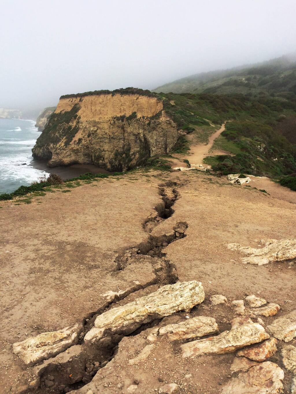 This recent but undated photo provided by Point Reyes National Seashore shows a fissure that has opened up atop Arch Rock within Point Reyes National Seashore on the Northern California coast north of San Francisco. One person is dead and another being treated for life-threatening injuries after the bluff at the end of a popular hiking trail collapsed Saturday, March 21, 2015. Two visitors were standing on the Arch Rock lookout point just before 6 p.m. when the bluff gave way. The pair fell about 70 feet and were covered with rocks and debris. One of the hikers was pronounced dead at the scene. The other was airlifted to a hospital. (AP Photo/Point Reyes National Seashore)