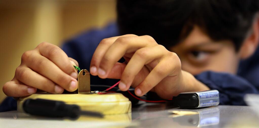 Tejaf Patel, 10, mounts coiled copper wire to create a rudimentary motor with the help of Keysight Technologies engineers at John Riebli Elementary School in Santa Rosa on Thursday. (JOHN BURGESS / The Press Democrat)