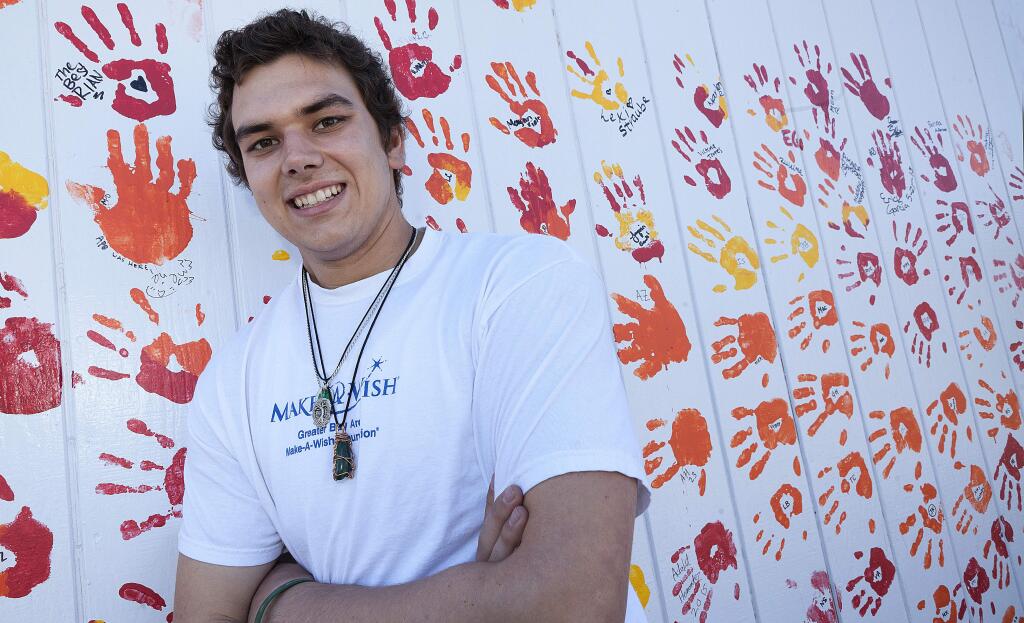 Standing in front of the senior class handprint mural, Mike Seelye has plans to lend a hand in life himself...