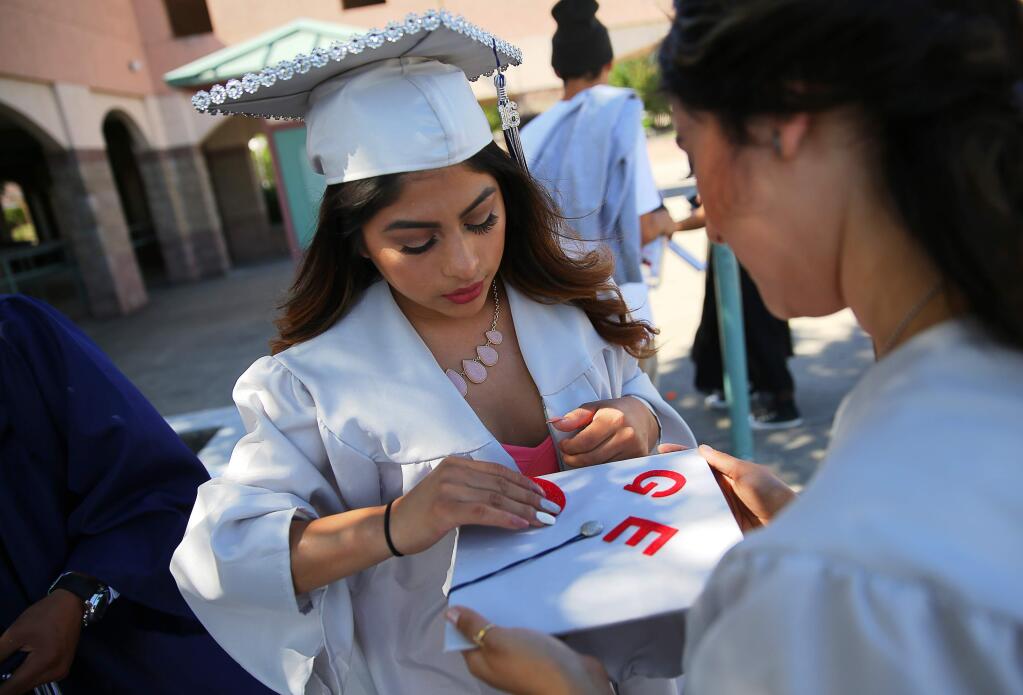 Katherine Beltran, left, helps Geovani Flores decorate her mortar board before the Elsie Allen commencement ceremony, in Santa Rosa on Friday, June 3, 2016. (Christopher Chung/ The Press Democrat)