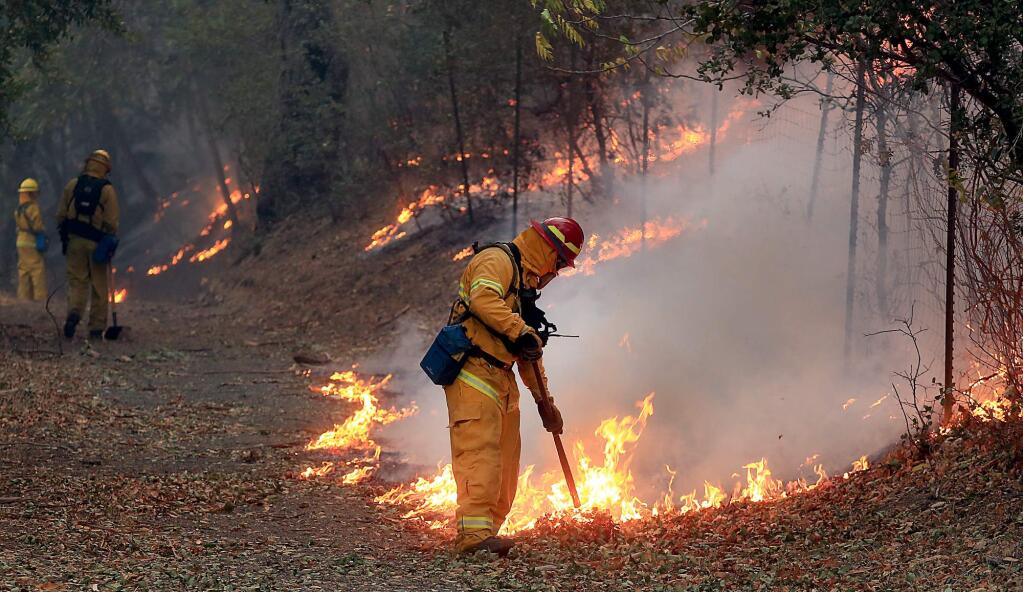 Firefighters drag fire as they monitor the progress of a backfire, Saturday Oct. 14, 2017 around the Buena Vista Winery grounds in Sonoma. (Kent Porter / The Press Democrat) 2017