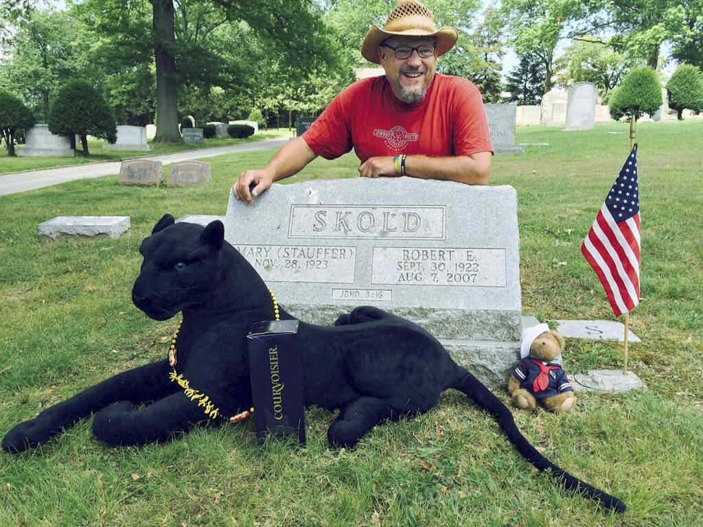 In this photo provided by Walter Skold, of Freeport, Maine, Skold poses Friday, Aug. 7, 2015, at the grave of his father in York, Pa. The Dead Poets Society of America founder visited his father's grave after completing his tour of 97 poets' graves in 70 days. With Skold is his mascot 'Raven,' a stuffed black panther that was given to him. (Walter Skold via AP)
