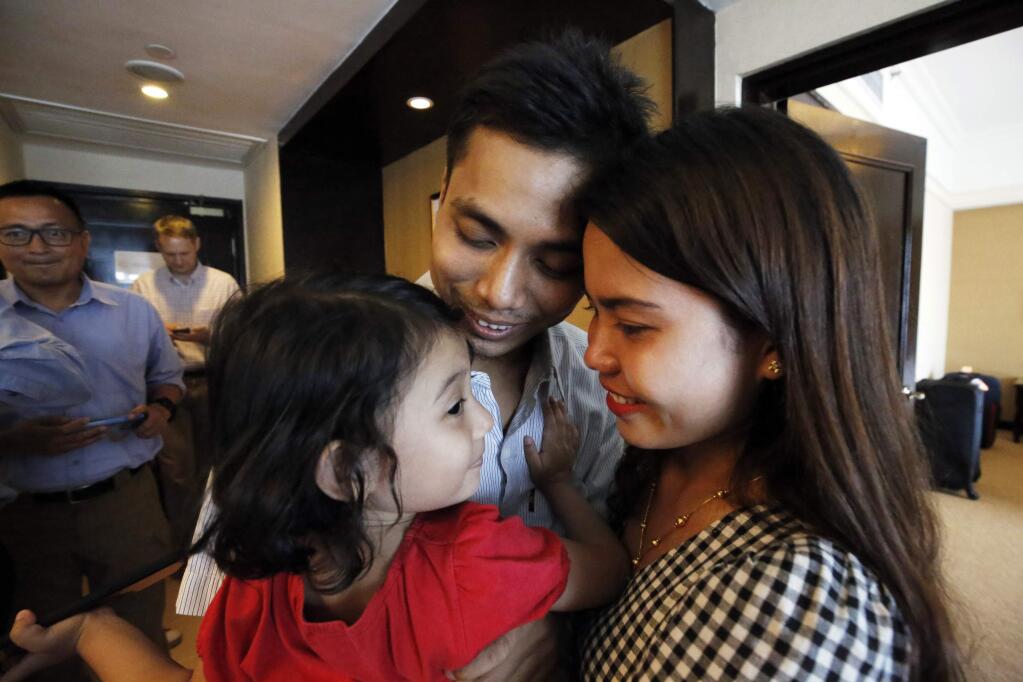 Reuters reporter Kyaw Soe Oo, center, holds his daughter with his wife Chit Su Win after being freed from prison, in Yangon, Myanmar, Tuesday, May 7, 2019. Two Reuters journalists who were imprisoned for breaking Myanmar's Official Secrets Act over reporting on security forces' abuses of Rohingya Muslims were pardoned and released Tuesday, the prison chief and witnesses said. (Ann Wang/Pool Photo via AP)