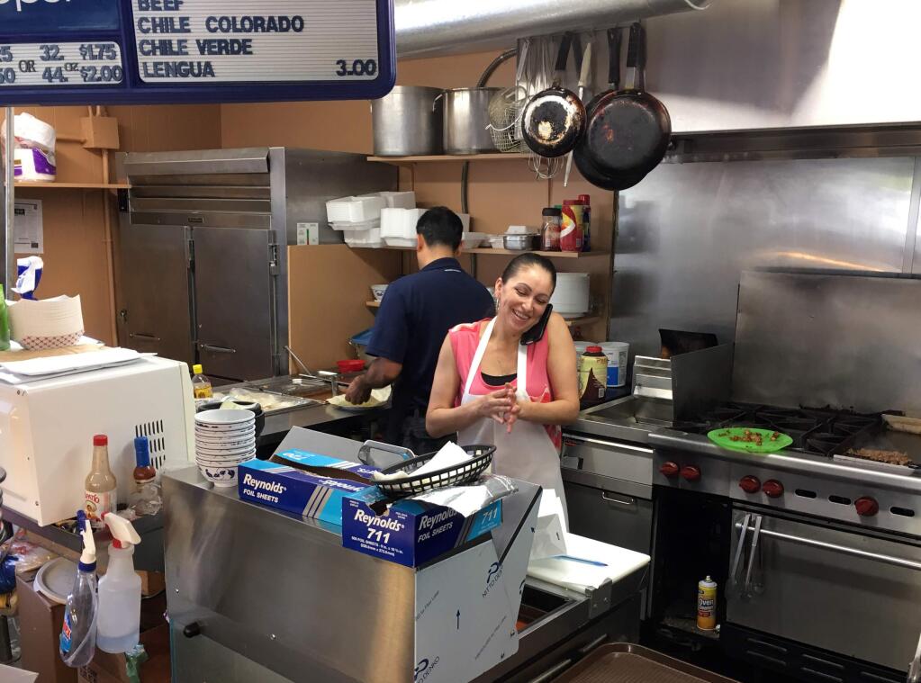 In this June 29, 2016 photo, Lety Toleda talks on the phone while working in her Taqueria Mi Tiendita cafe in Prineville, Ore. Toledo has seen business improve as the city rides the digital revolution. When timber was king, Crook County was the nation's top producer of ponderosa lumber. But with the catastrophic decline in the timber industry, and then the global recession, suddenly the digital revolution is providing the county and its main town, Prineville, with a rare second chance. (AP Photo/Andrew Selsky)