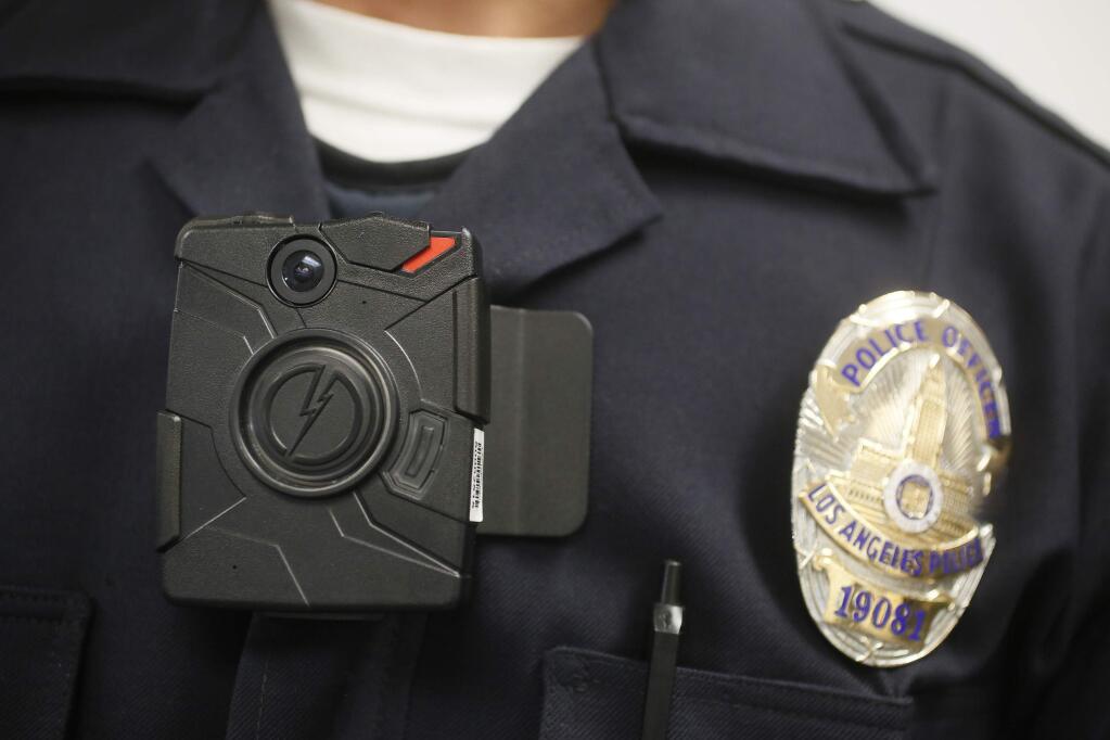 FILE - This Jan. 15, 2014 file photo shows a Los Angeles Police officer wearing an on-body cameras during a demonstration for media in Los Angeles. Governments must bear the costs of redacting police body camera video before making it public, the California Supreme Court ruled Thursday, May 28, 2020, in a decision that was hailed by media organizations but will be costly for cities and counties. (AP Photo/Damian Dovarganes,File)