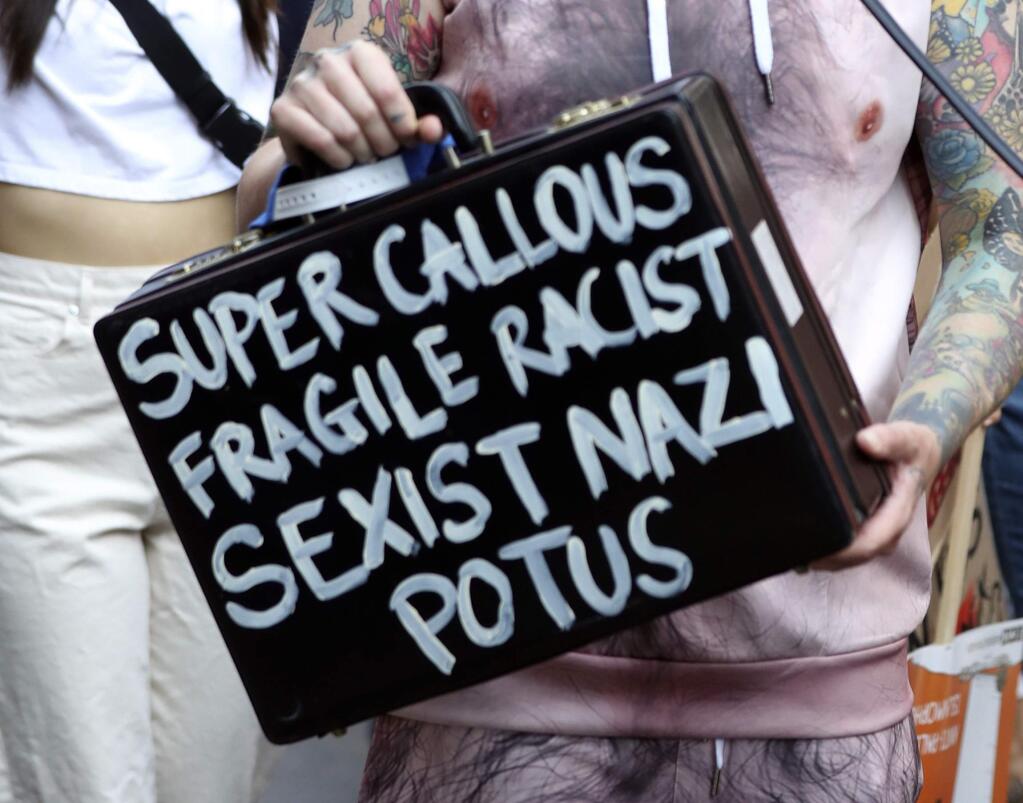 A protester holds a suitcase bearing a message at the 'Stop Trump' Women's March in London, Friday, July 13, 2018. 'Super Callous Fragile Racist Sexist Nazi POTUS”: That placard, referencing Mary Poppins, is just one of the many humorous and creative signs seen at the huge rallies protesting U.S. President Donald Trump's visit to Britain. Huge crowds poured into London's streets Friday to protest Trump's policies, from immigration to race relations to women and climate change. (Gareth Fuller/PA via AP)