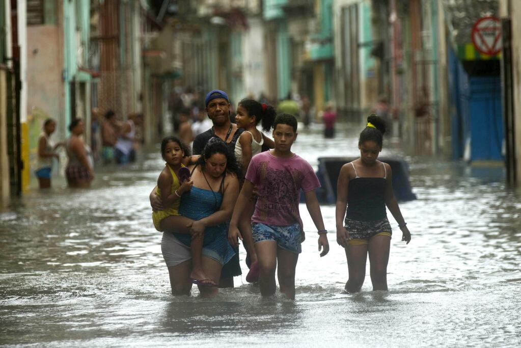 People walk through flooded streets in Havana after the passage of Hurricane Irma in Cuba, Sunday, Sept. 10, 2017. The powerful storm ripped roofs off houses, collapsed buildings and flooded hundreds of miles of coastline after cutting a trail of destruction across the Caribbean. There were no immediate reports of deaths in Cuba, a country that prides itself on its disaster preparedness, but authorities were trying to restore power and clear roads. (AP Photo/Ramon Espinosa)