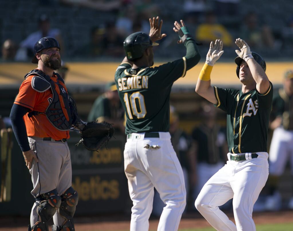 Oakland Athletics' Marcus Semien (10) and Boog Powell celebrate Powell's two-run home run against the Houston Astros during the eighth inning of a baseball game, Sunday, Sept. 10, 2017, in Oakland, Calif. The A's won 10-2, and swept the four-game series. (AP Photo/D. Ross Cameron)