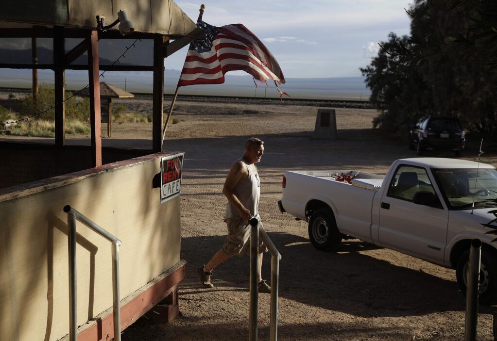 Carl Cavaness walks to the Nipton Trading Post, Thursday, Aug. 3, 2017, in Nipton, Calif. American Green Inc., one of the nation's largest cannabis companies, announced it has bought the entire 80 acre California desert town of Nipton. (AP Photo/John Locher)