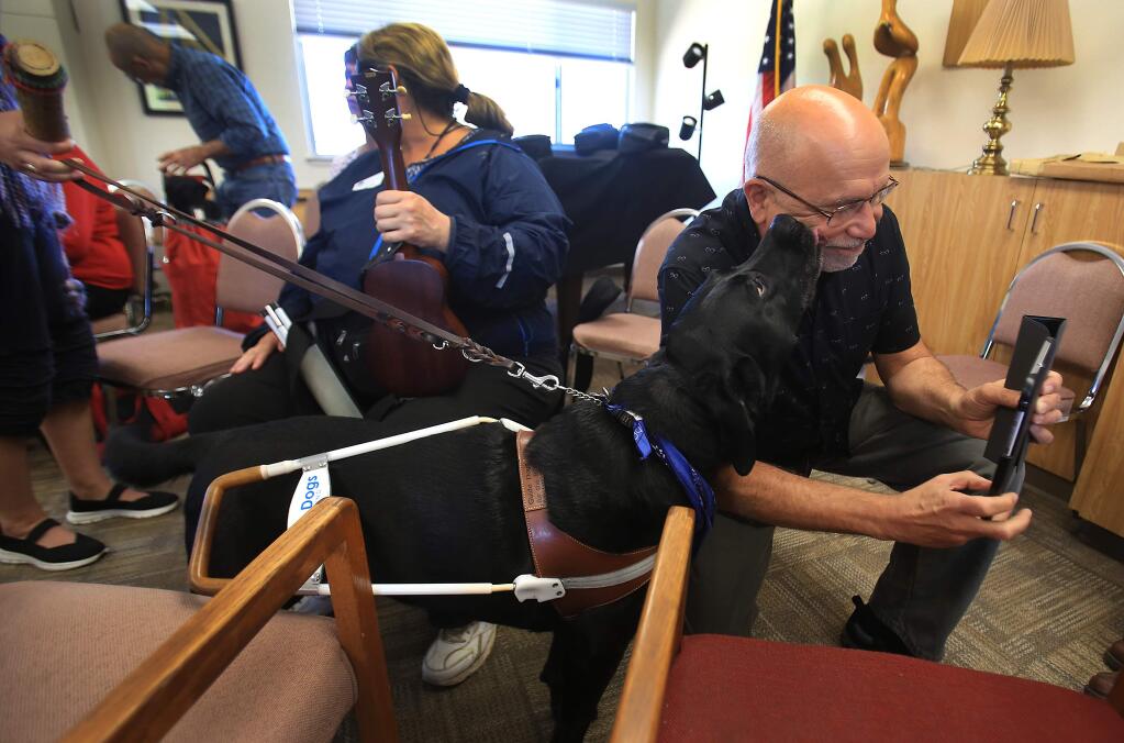 Caesar the dog nuzzles Earle Baum Center volunteer Geno Russo who teaches music to visually impaired clients at Earle Baum in Santa Rosa, Friday Sept. 16, 2016. The dog belongs to his friend Denise Vancil, an independent living skills teacher at the facility as well as being visually impaired. (Kent Porter / The Press Democrat) 2016