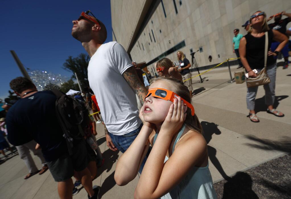 Lilly Kingsbury, 9, joins her father, Ryan, both of Denver in using special glasses as residents gather at the Denver Museum of Nature and Science to observe the partial solar eclipse as it passes over City Park in east Denver on Monday, Aug. 21, 2017. (AP Photo/David Zalubowski)