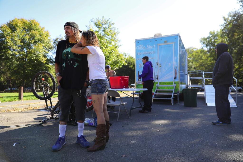 Ricky Owens, left, and Jennifer Stroude hang out in Doyle Community Park after using the Clean Start portable shower, in Santa Rosa on Thursday, October 5, 2017. (Christopher Chung/ The Press Democrat)