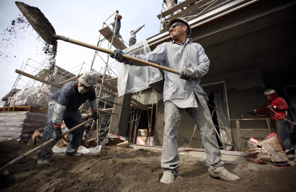 Tomas Garfias, center, and of Daniel Lino, left, of Ace Plastering shovels sand into a mixer for plaster to apply on the new homes on the Blue Mountain Homes Spring Brook Community project on Wishing Well Way off Fulton Road in Santa Rosa Wednesday, February 4, 2015. (Crista Jeremiason/ The Press Democrat)